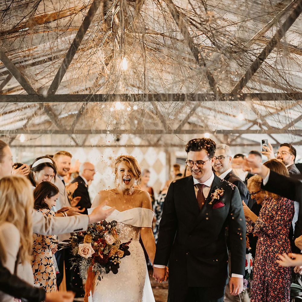 Bride walks through colourful confetti exit with her groom after bespoke wedding ceremony at The Dreys