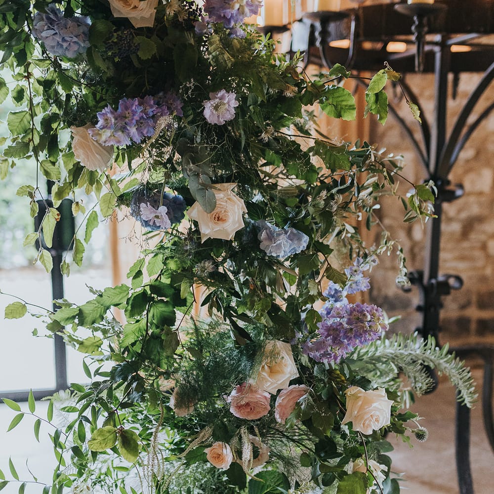 pastel pink rose and blue thistle wedding flowers on floral arch 