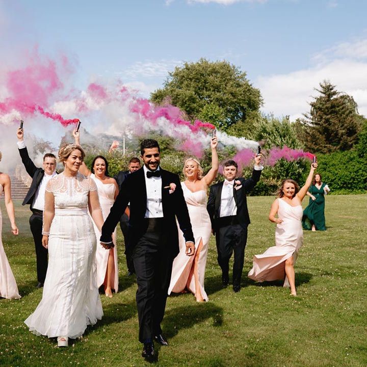 Pink and white colourful smoke bomb wedding photo with the whole wedding party in pink theme outfits 
