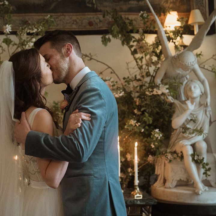 Groom in blue velvet blazer kissing the bride for their first kiss as a married couple 