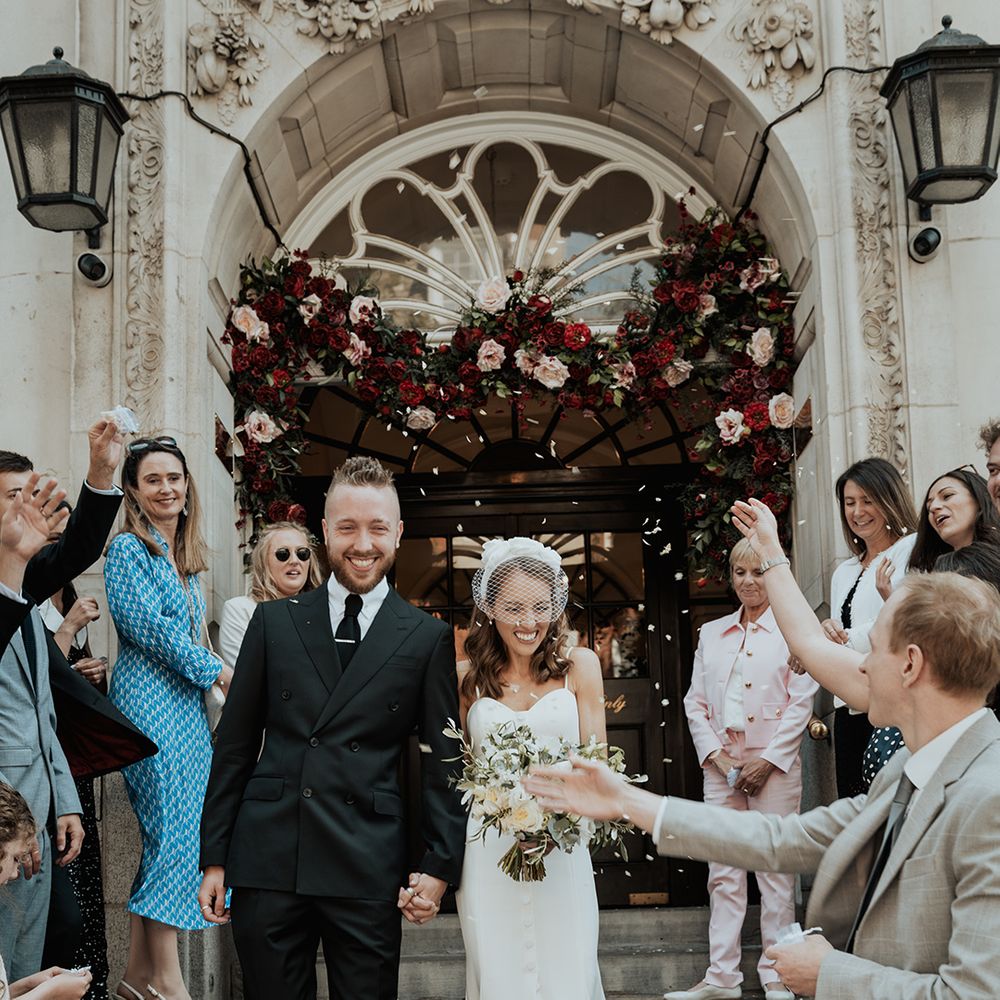 confetti moment on the steps of Chelsea Town Hall with groom in a black suit and bride in separates 