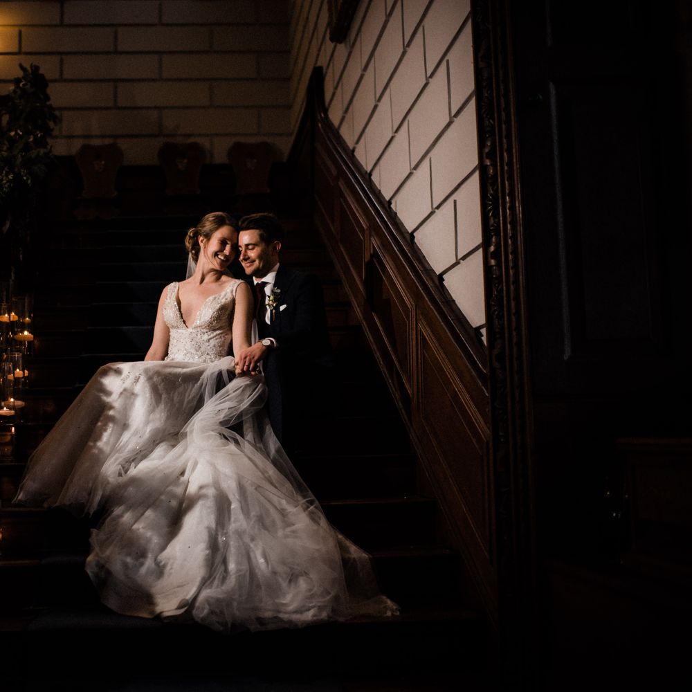 Bride & groom sit together on the stairs holding hands