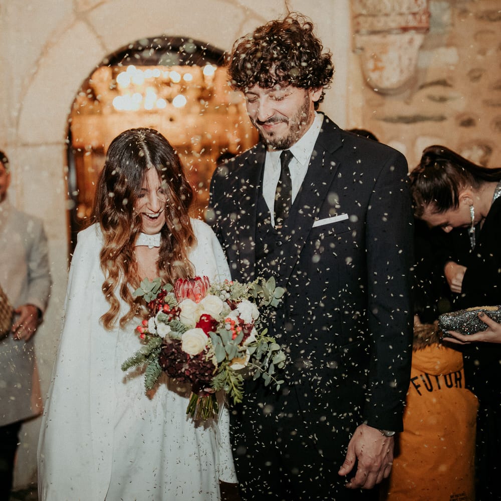 The bride and groom leaving their church wedding ceremony having confetti thrown over them
