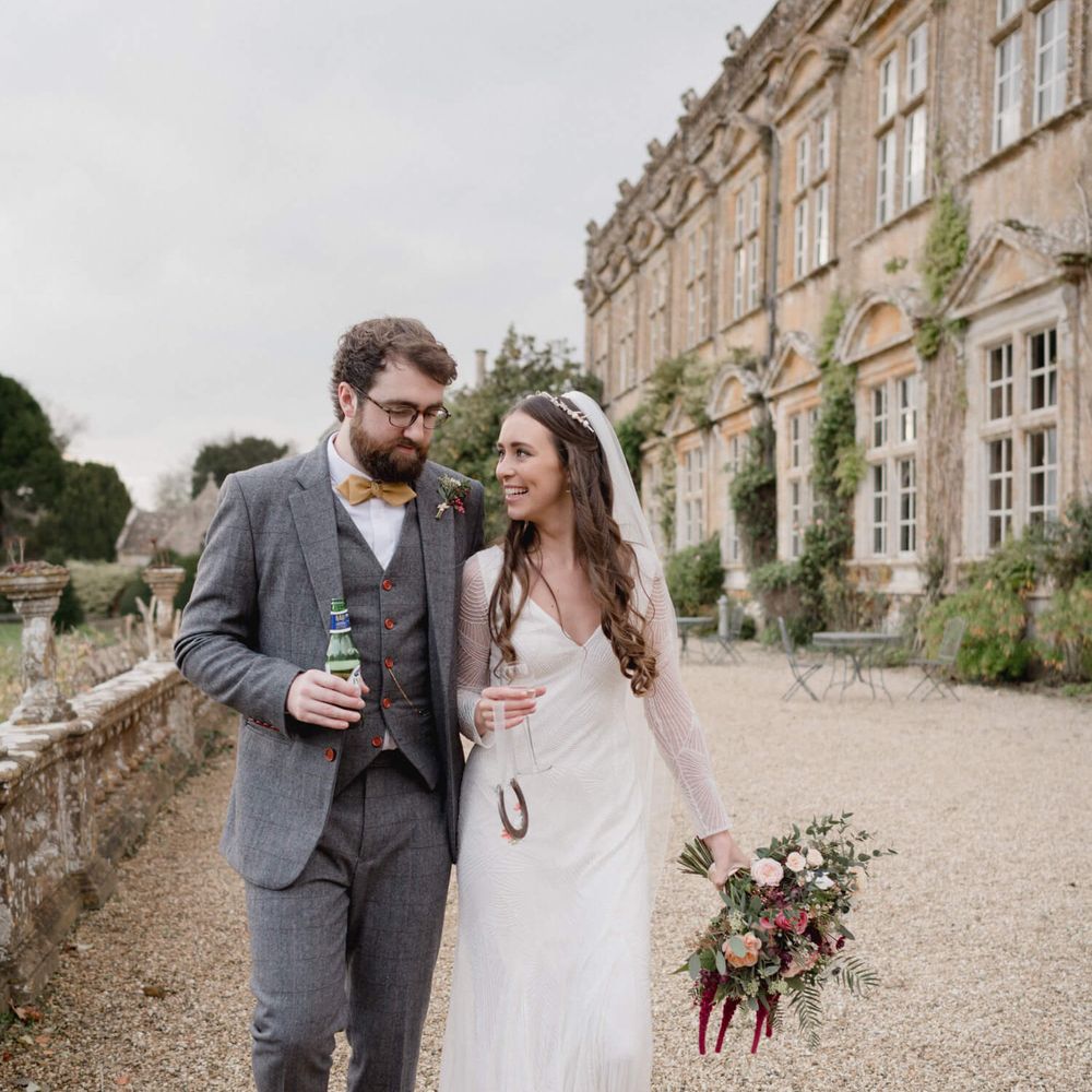 Bride and groom outside Brympton House | Bride holding champagne groom with a bottle of Peroni 