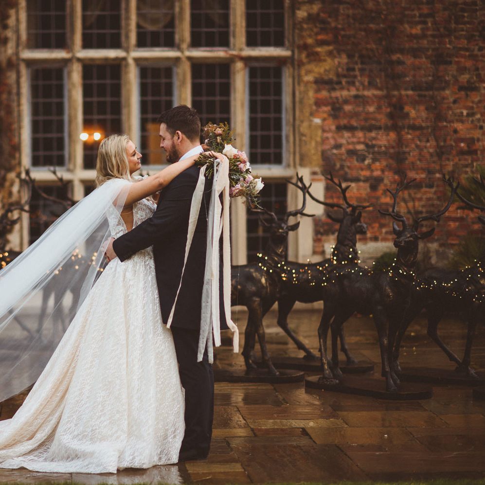 Bride in a princess wedding dress with bespoke cape holding a blush bouquet tied with lots of ribbon 