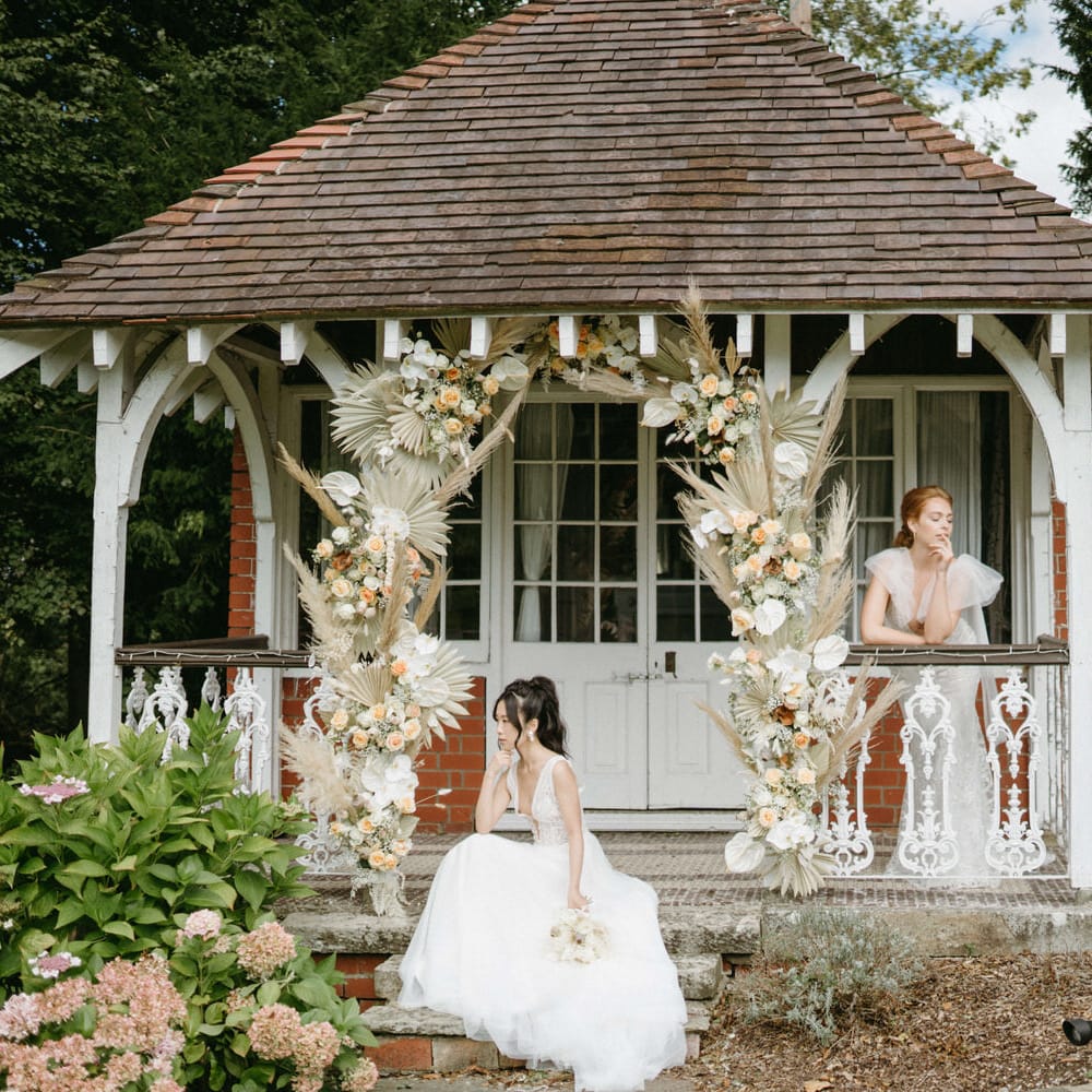 Two brides at Berwick Lodge with neutral colour flower arch for boho inspired wedding shoot