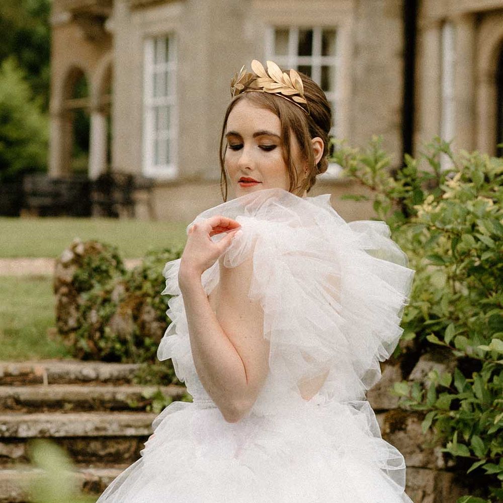 Bride in a tulle wedding dress with brown eyeshadow and black eyeliner wearing a gold crown 