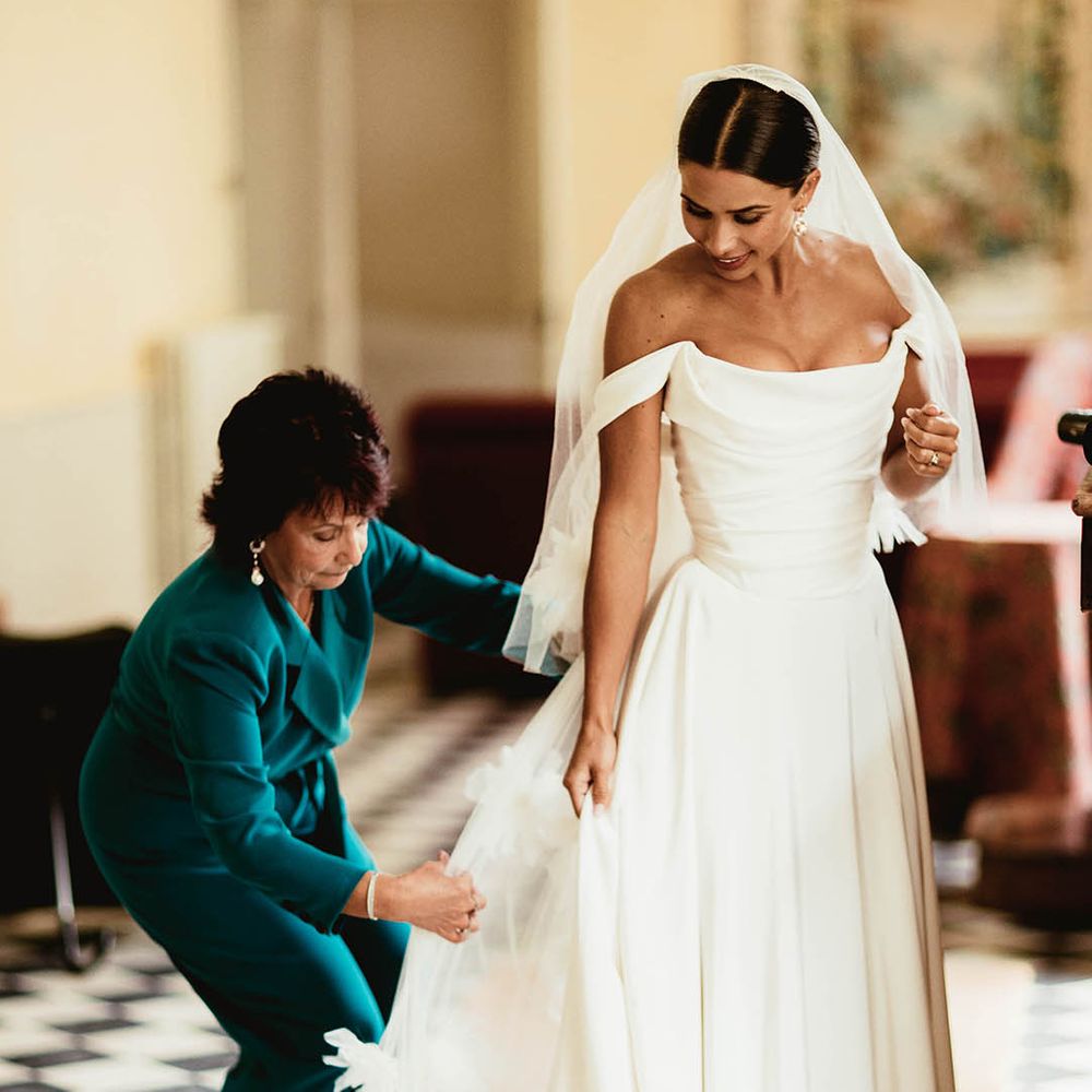 Mother of the bride helps bride with her gown on her wedding day