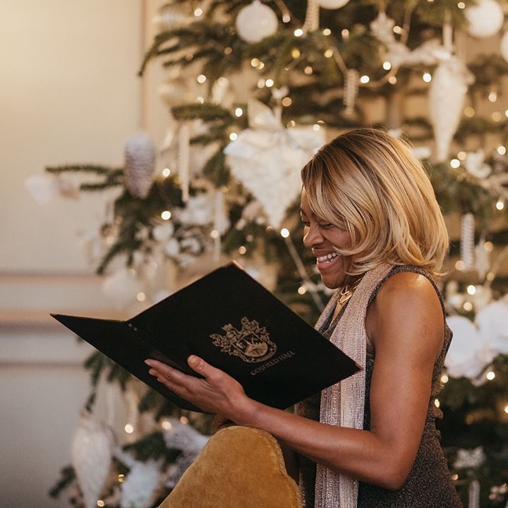 Celebrant reads during wedding ceremony whilst stood in front of Christmas tree 