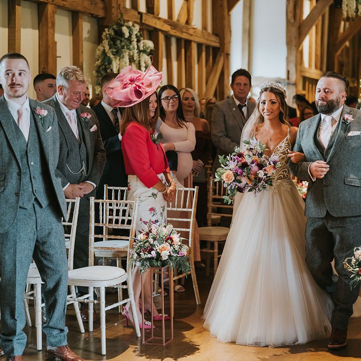 Bride walks down the aisle in tulle skirt with deep plunging v neck wedding dress with sparkles
