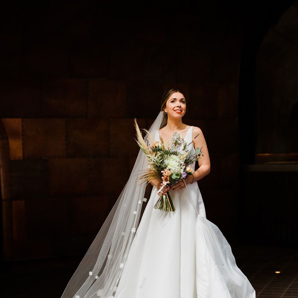 Bride wearing veil with 3D flowers and v neck wedding dress with large wedding bouquet including pampas grass