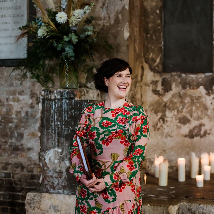 Celebrant in bright coloured floral dress for industrial wedding with candles 