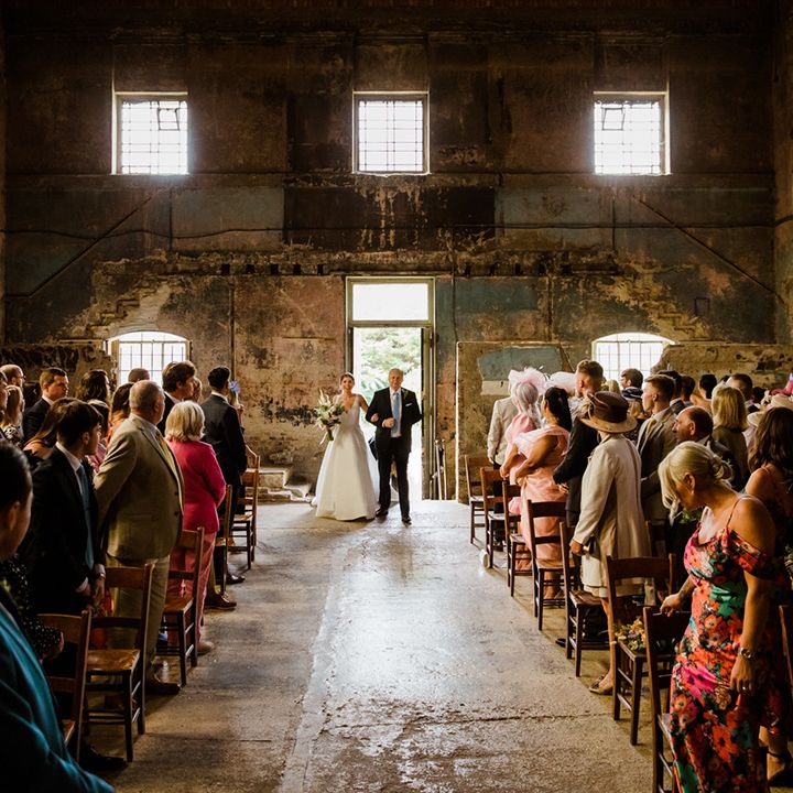Father of the bride makes the entrance with the bride at industrial Asylum Chapel wedding in London