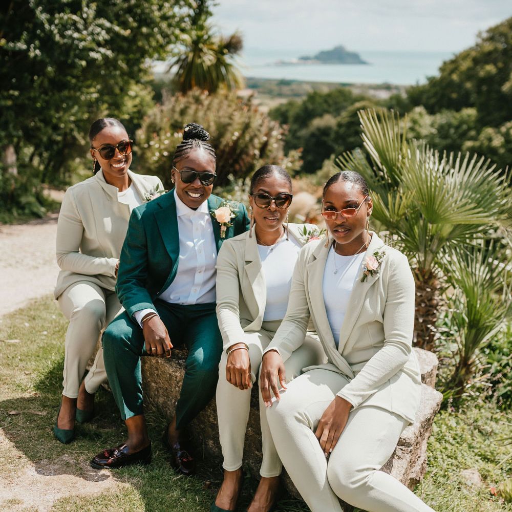Bridal party in wedding suits. The Black bride wears a dark green suits and the bridal party light green bridesmaids suits