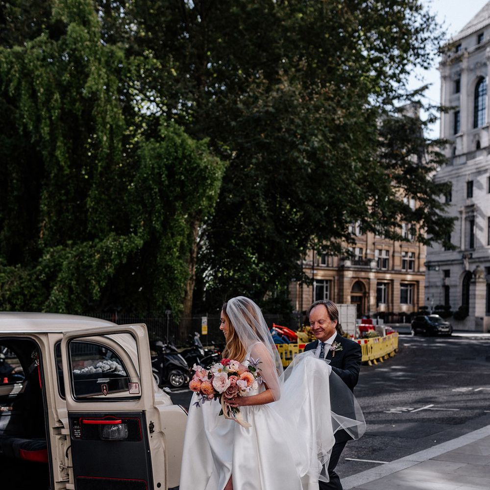 Bride in a Karen Willis Holmes wedding dress and grey jewel encrusted Manolo Blahnik mules getting into a cream London cab 
