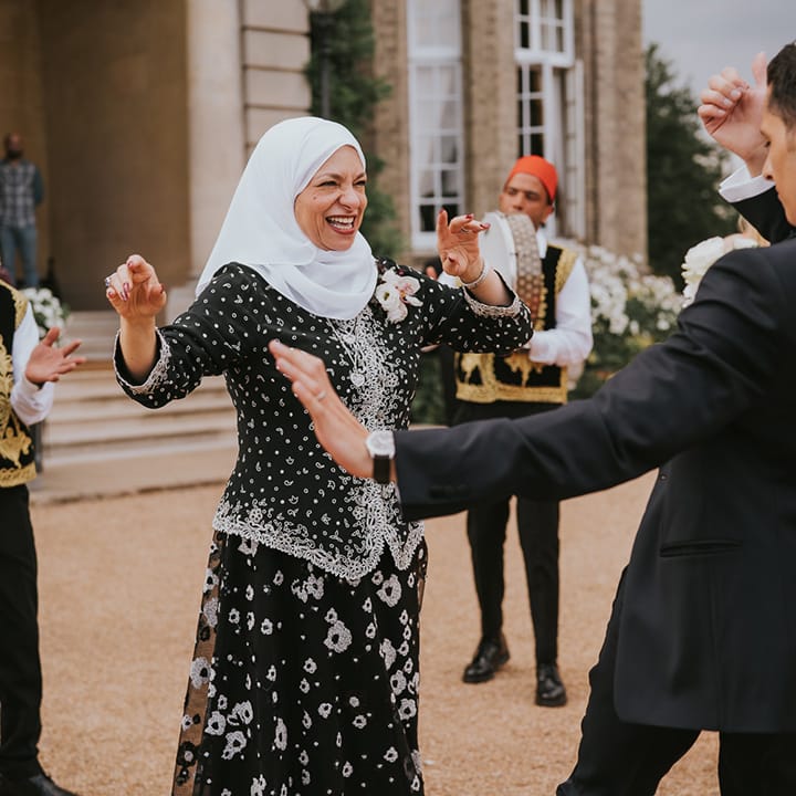 Groom in black tie dances with his mother with the Zaffa band 