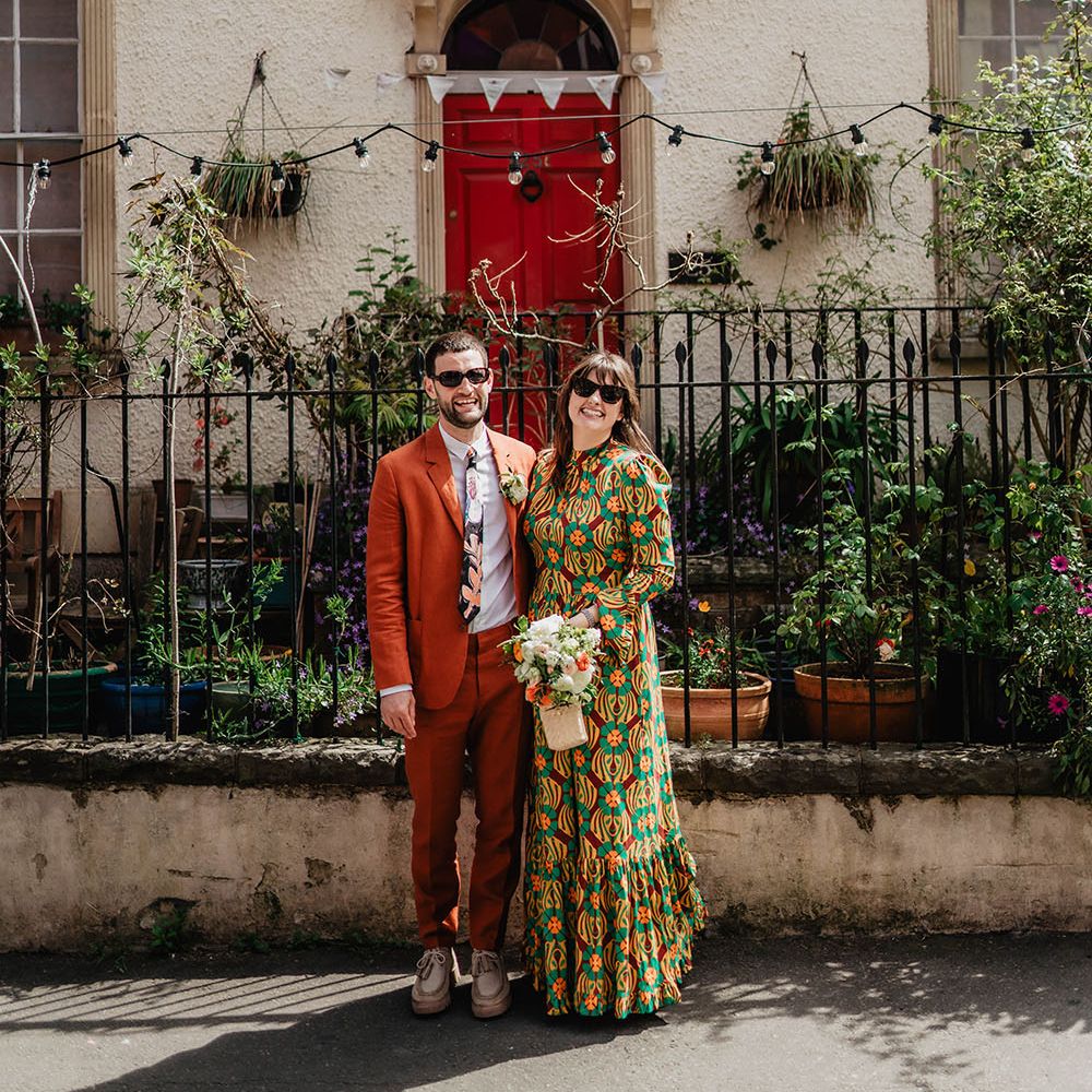Bride & groom laugh and smile brightly outdoors on their wedding day in Bristol whilst wearing sunglasses 