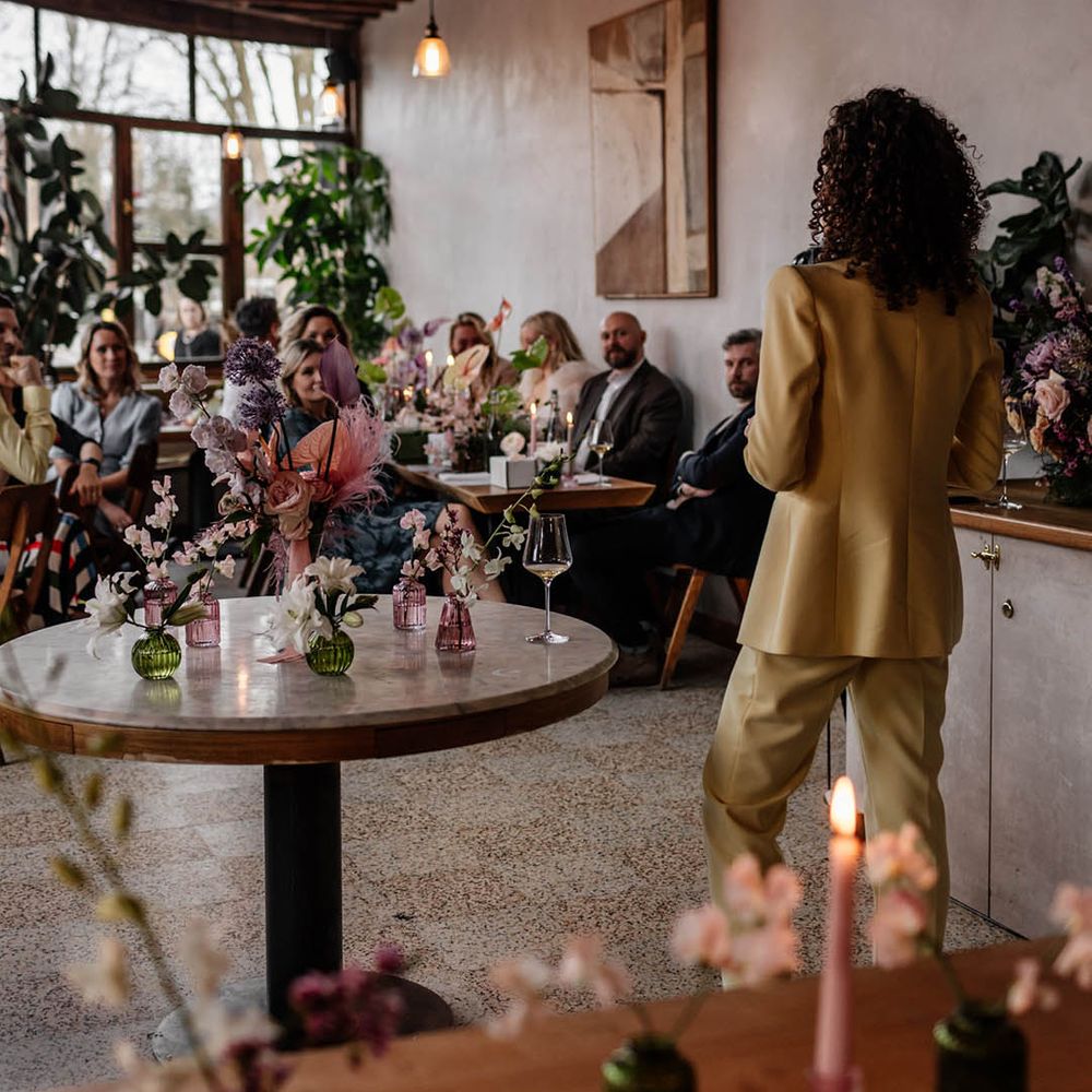 bridesmaid with natural curly hair in a yellow bridesmaid suits giving a wedding speech 