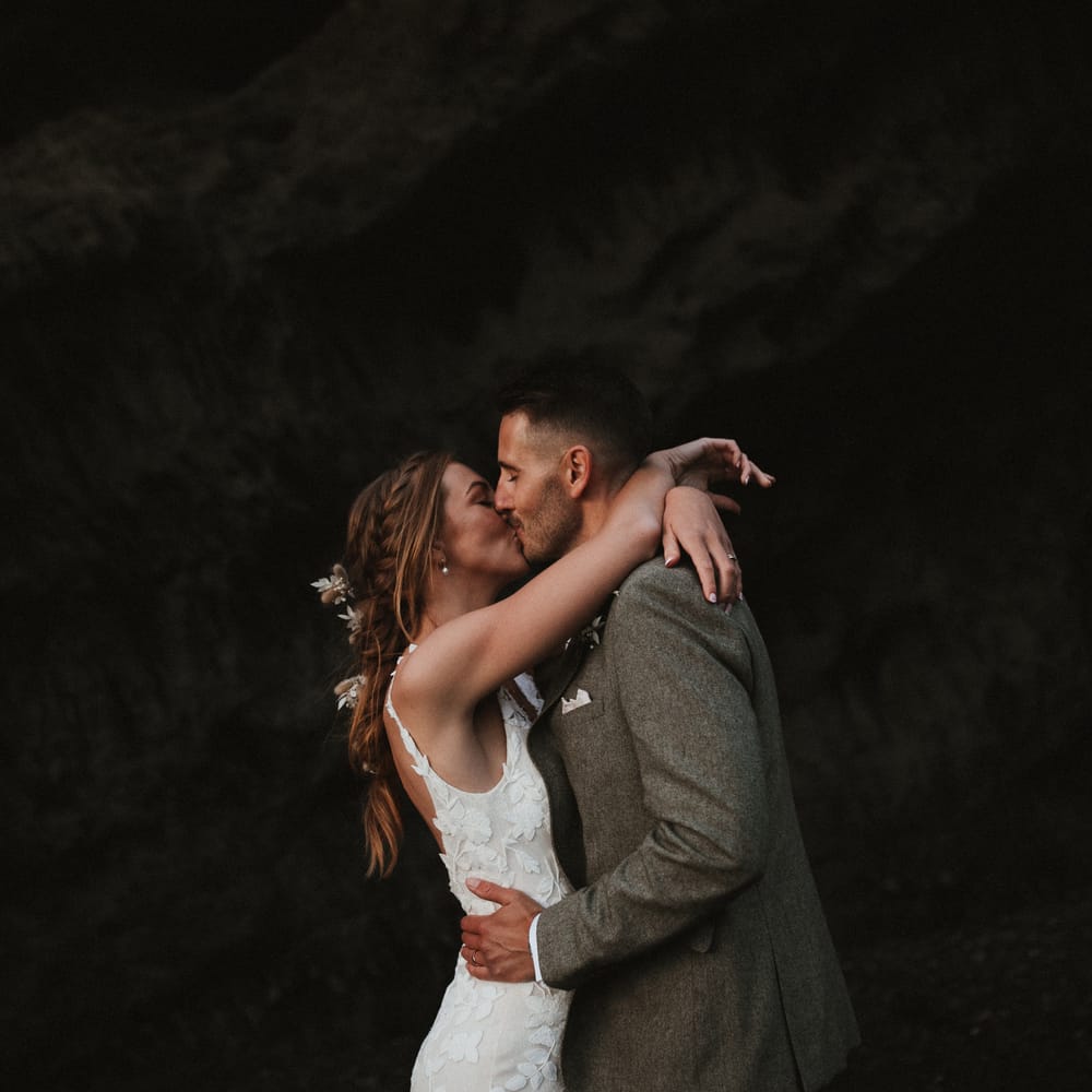 Bride & groom embrace outdoors on the beach for couples portraits after wedding ceremony