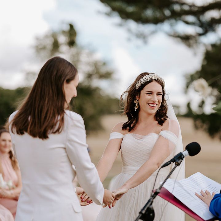 The bride hold both hands together as they participate in their same sex wedding ceremony 