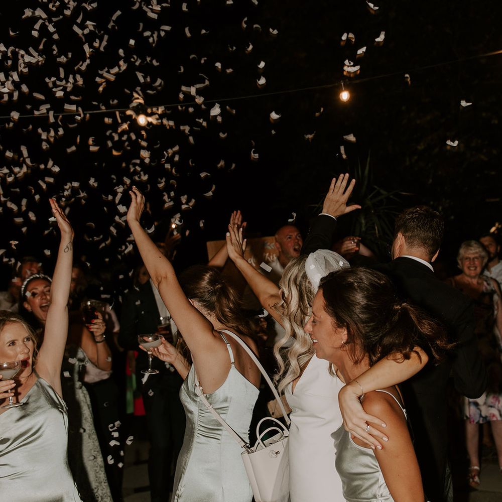 The bride in her Made With Love wedding dress with flower applique veil dances with the bridesmaids in sage green dresses for the reception
