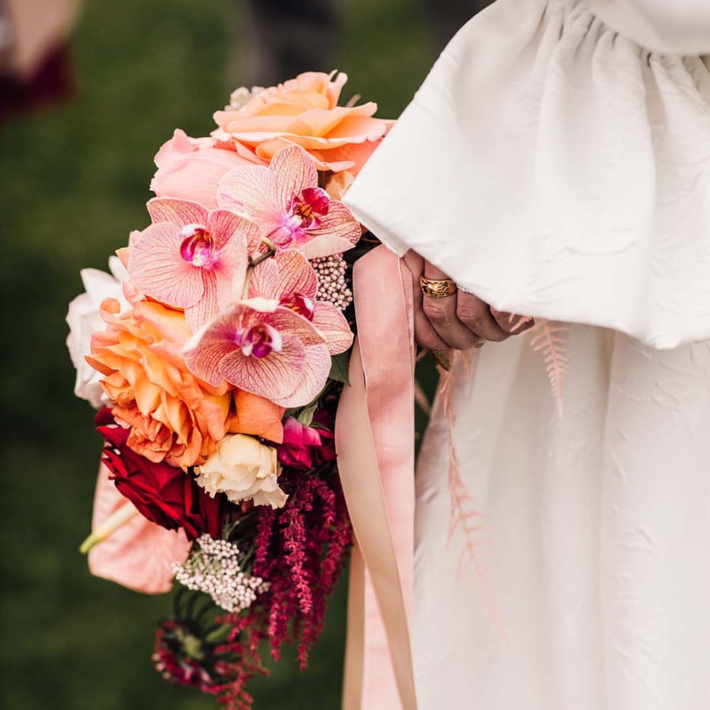 Bride holding the pink wedding bouquet with orchids and anthuriums tied with pink ribbon 