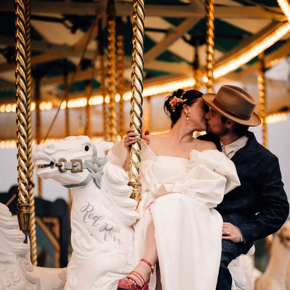 The bride and groom ride on the carousel at Preston Court in Kent 
