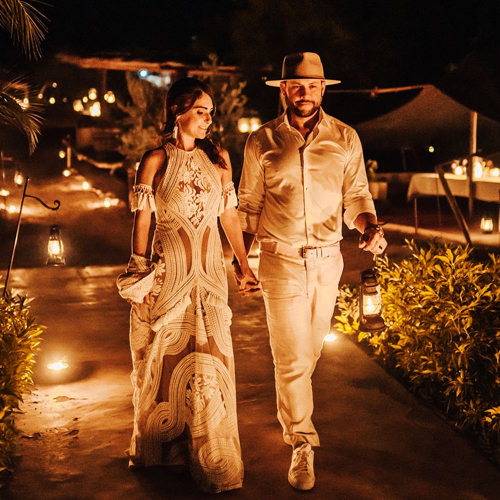 Bride and groom walk together around the softly lit wedding venue 