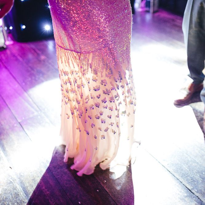 Brides iridescent dress glowing in the neon lights on the dance floor