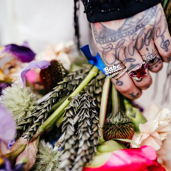 Bride with staking rings and hand tattoos holding her wedding bouquet 
