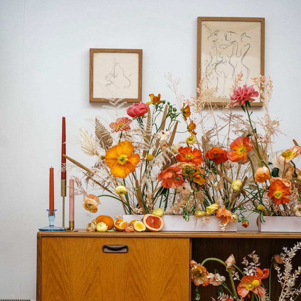 70s wedding decor with fresh poppies and dried flowers, tapered candles and citrus fruits