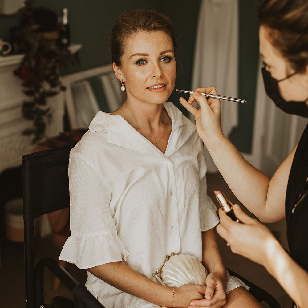 Bride on the wedding morning in white short pyjamas with smokey eye shadow and peach lipstick wedding makeup 