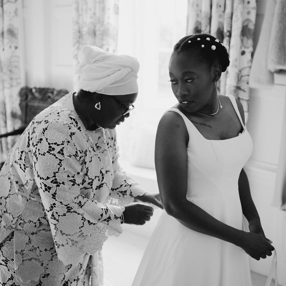 Black African Mother of the bride doing up her daughters Essense of Australia wedding dress 