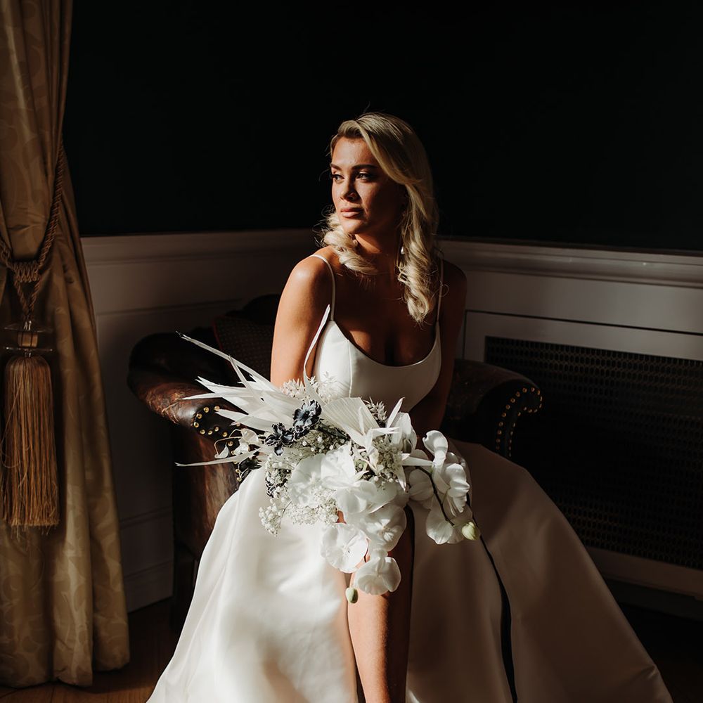 Bride in a princess wedding dress with side slit holding a tropical wedding bouquet with orchids 