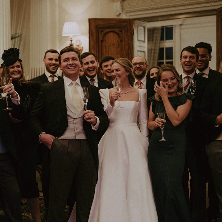 Wedding guests and bride in long white Suzanne Neville wedding dress