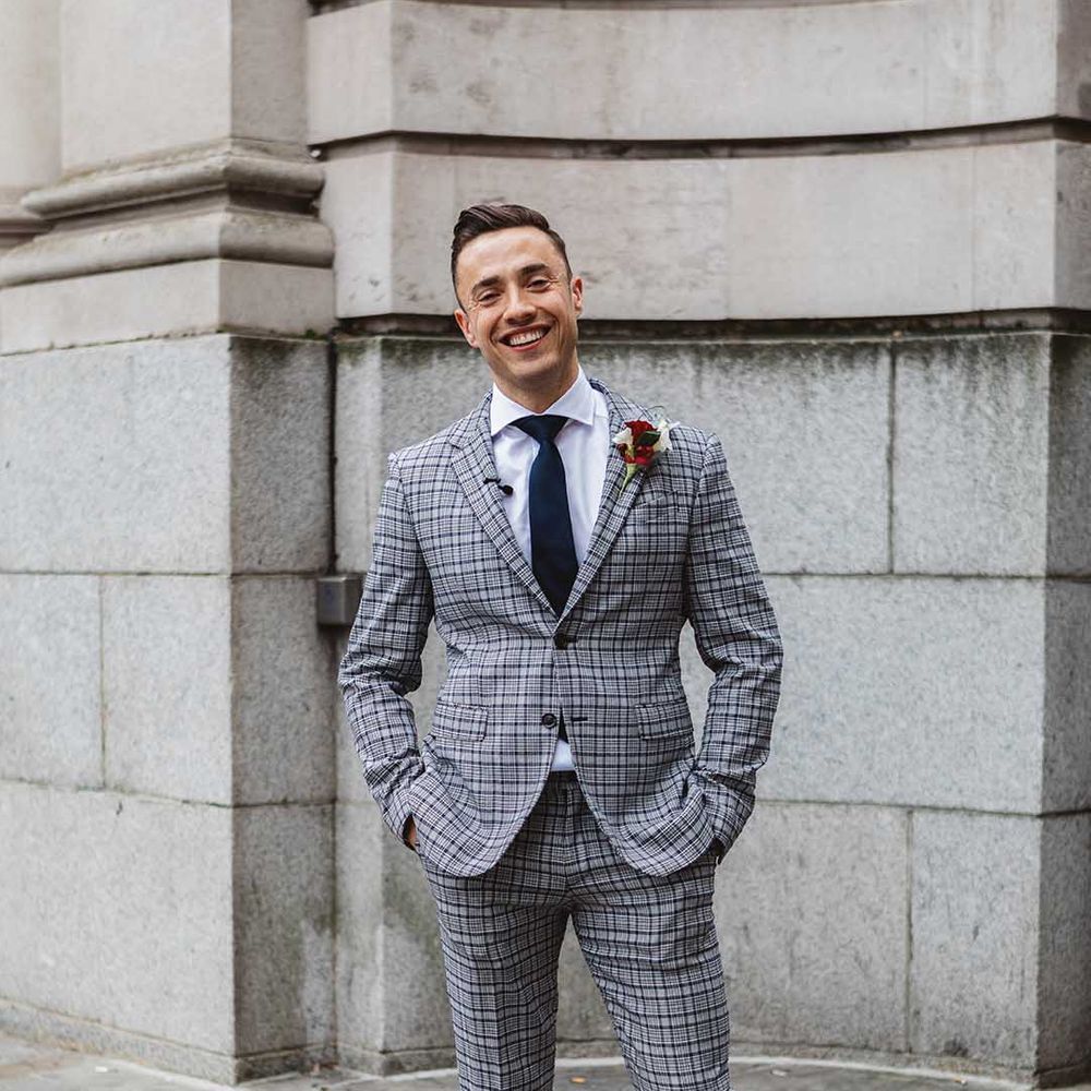 Groom wears grey striped suit complete with tie and floral buttonhole 