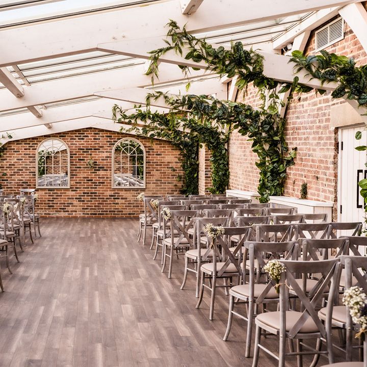 Wedding ceremony room at Foxtail Barns wedding venue with grey chairs and decorative greenery