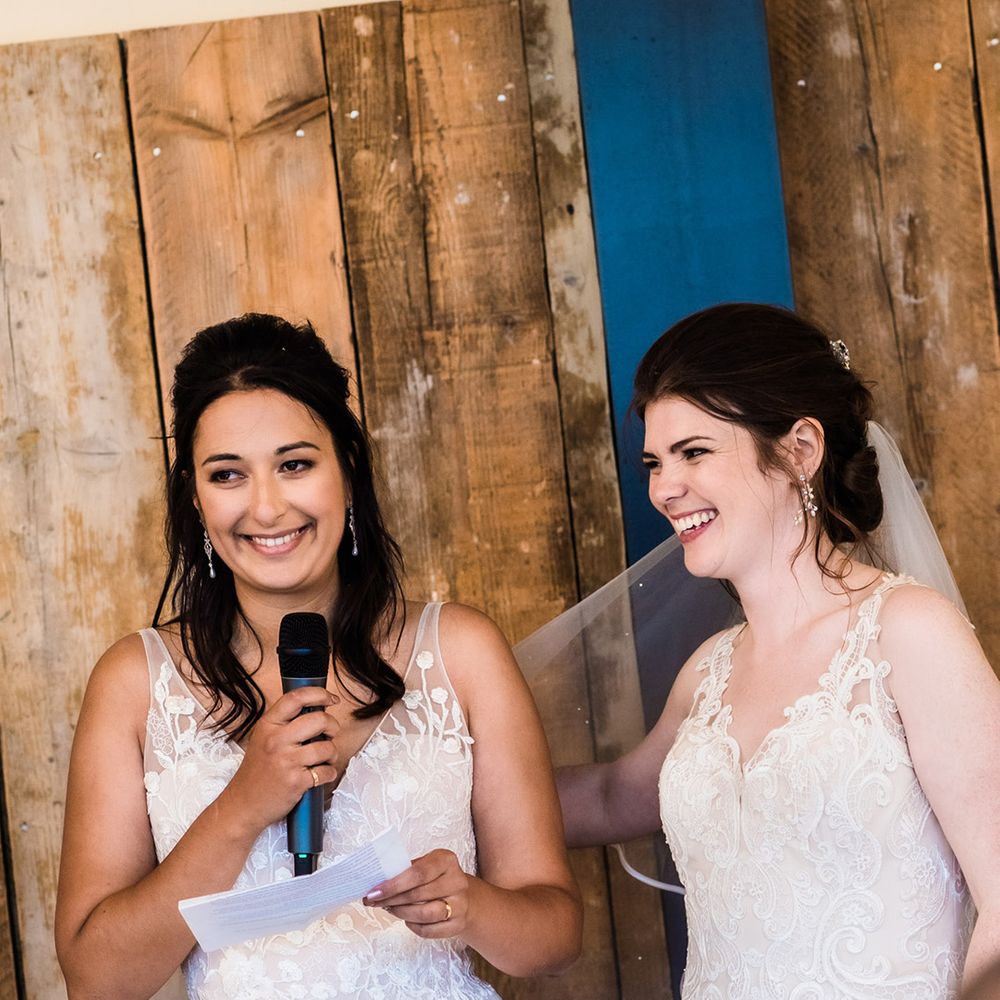 Brides stand up together as they do a bridal speech for their wedding