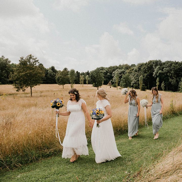 Brides are followed by their bridesmaids in green dresses and the rest of the wedding party 