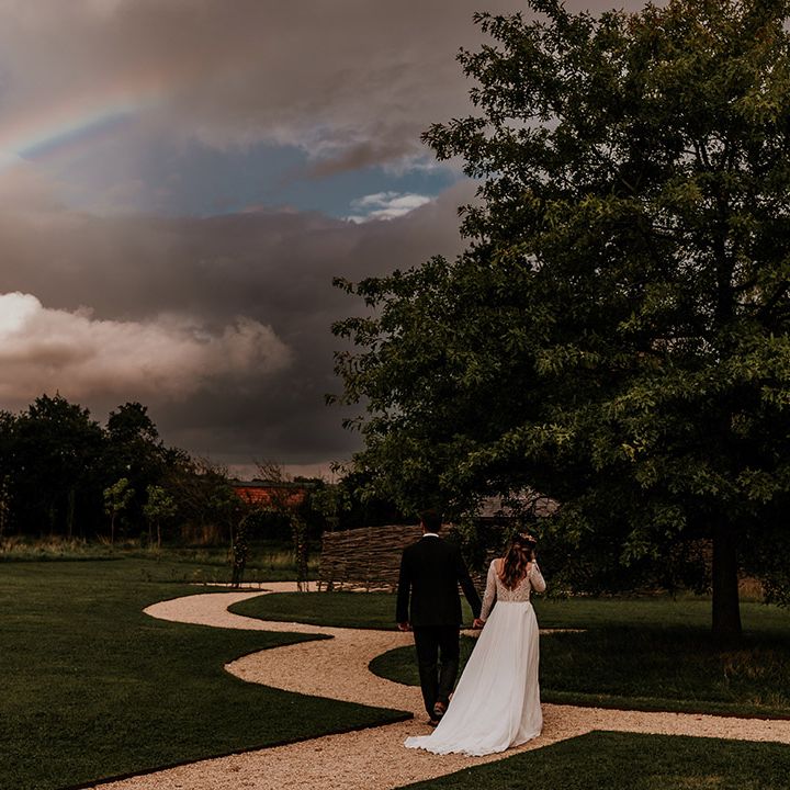 Bride and groom walk around the grounds of Silchester Farm as a rainbow starts to show