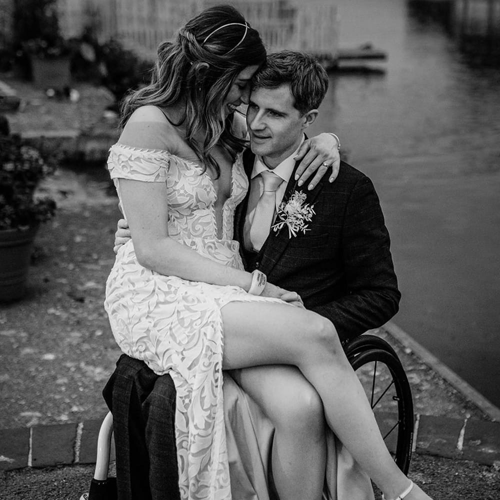 Bride sits on the groom's lap and rests her forehead against the groom's head 