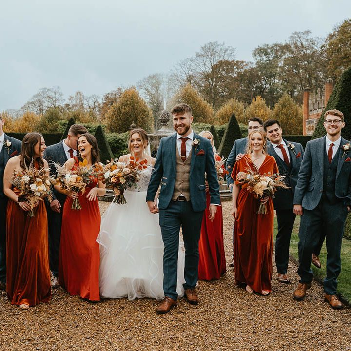 Bride in Blush by Hayley Paige wedding dress, bridesmaids in orange dresses and groom and groomsmen in blue suits, brown waistcoats and burnt orange ties 