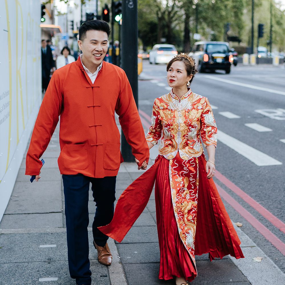 Bride & groom wear traditional Chinese attire as they walk down the street with one another on their wedding day