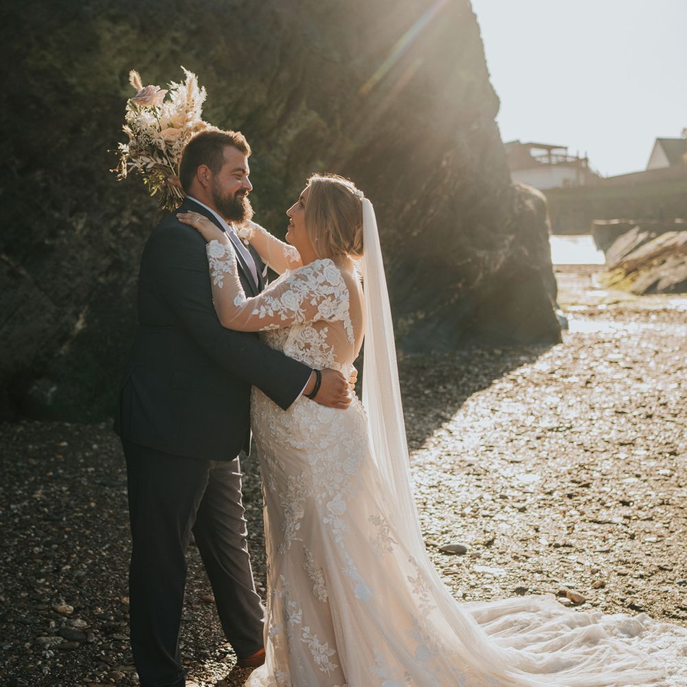 Bride embraces her groom outdoors during coastal couples portraits at Watermouth Cove
