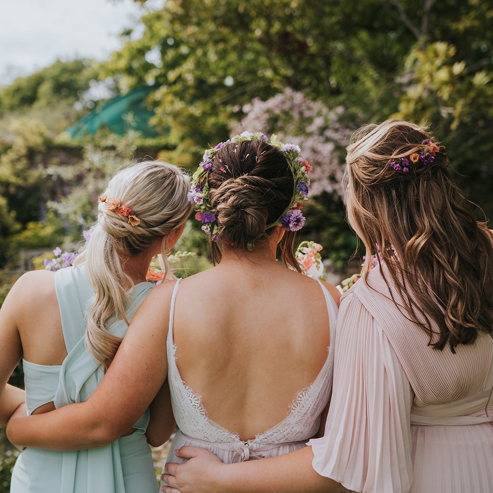 Bride and her bridesmaids wear colourful florals in their hair for outdoor wedding 