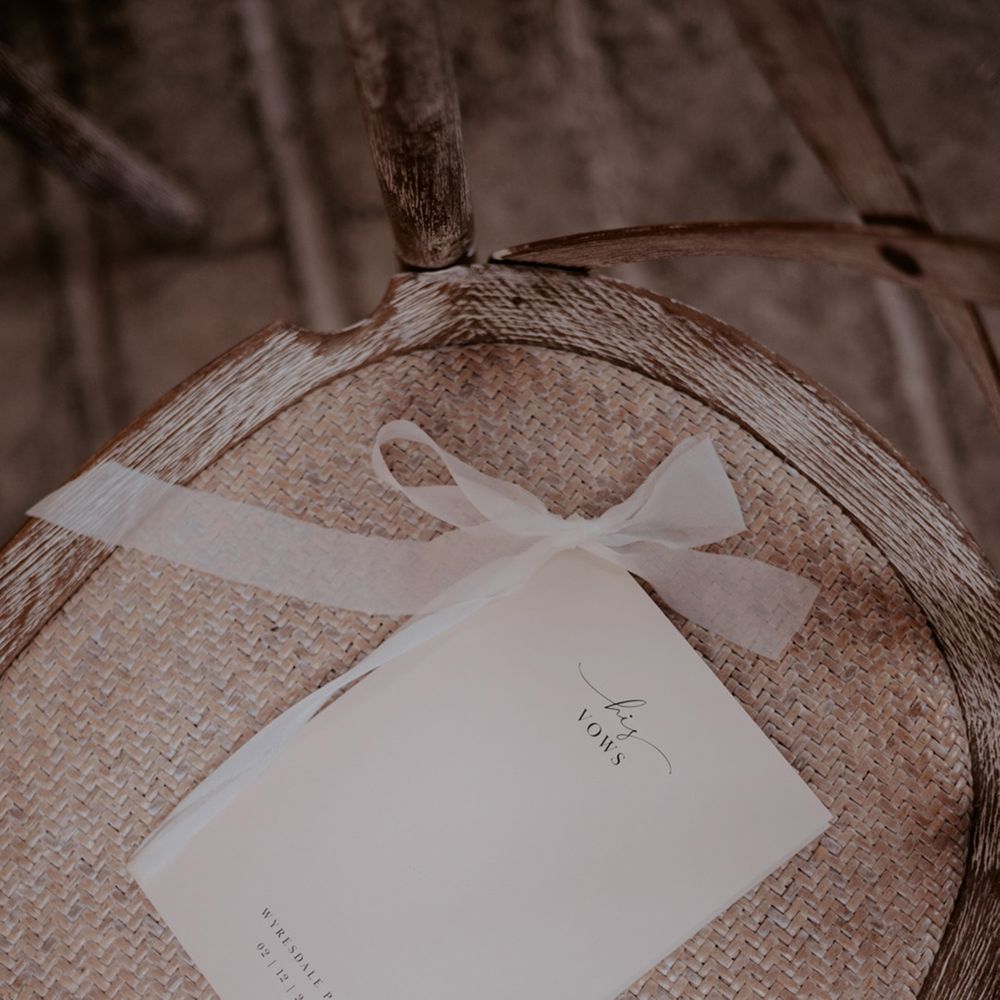 Classic and minimal wedding vow booklet tied with white ribbon for the traditional wedding day 