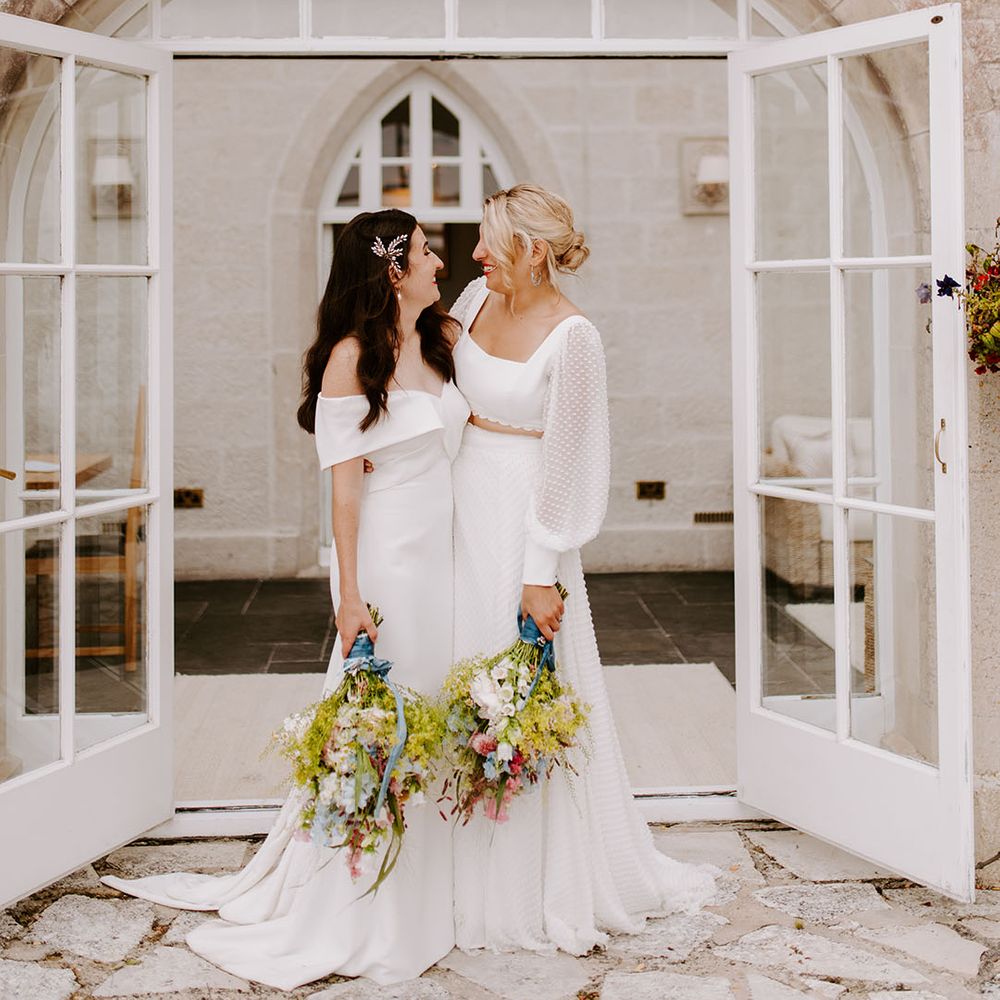 Romantic whimsical wedding with the two brides posing together carrying their wildlflower wedding bouquets for whimsical wedding 