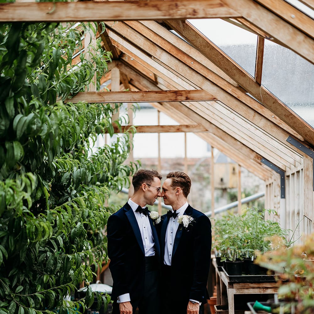 Two grooms wearing tuxedos at Deer Park country house wedding venue with their pet dog as a dog of honour 