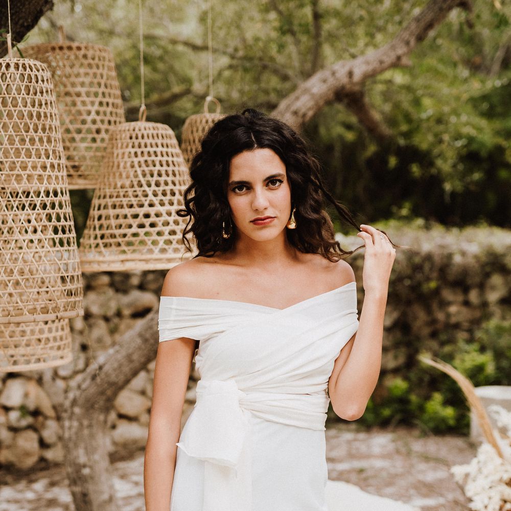 Bride stands outside wearing white boho gown
