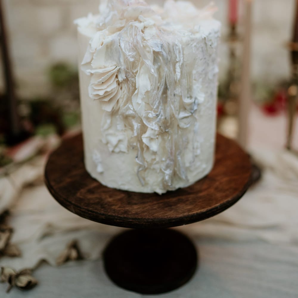 single tier wedding cake with intricate design on a wooden cake stand 